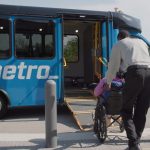 Call‑A‑Ride operator helps rider to board a Call‑A‑Ride van. The doors are open and the ramp is lowered.